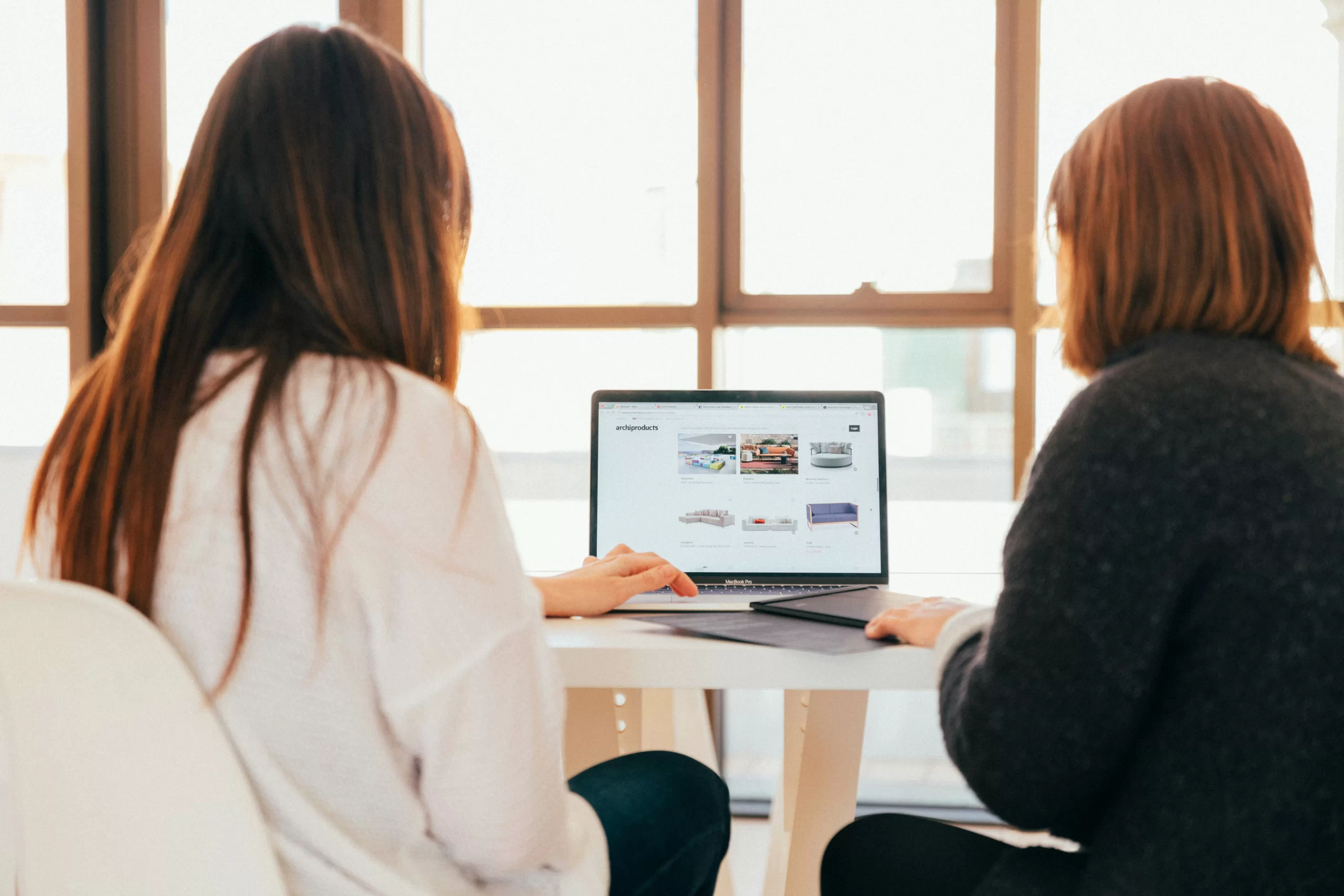 The backs of two women looking at a computer screen. Photo: Kobu Agency